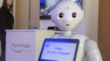 Er darf beim Digital-Gipfel nicht fehlen: Der humanoide Roboter Pepper. Er könnte eines Tages Pflegekräfte entlasten. Mehr dazu: <a href=&quothttps://www.bmbf.de/de/wissenschaftsjahres-2018-roboter-fuer-die-altenpflege-der-zukunft-6201.html">Hier</a>.