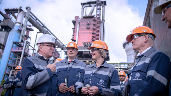 Im Rahmen ihrer Pressereise besucht Anja Karliczek ein Stahlwerk von ThyssenKrupp. Hier steht sie gemeinsam mit einem Betriebsleiter und dem Vorstandsvorsitzenden von ThyssenKrupp, Guido Kerkhoff, vor Hochofen 9.