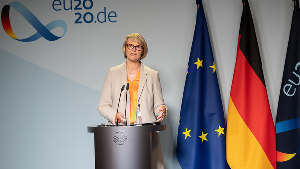 Ministerin Karliczek steht an einem Rednerpult, im Hintergrund ist die deutsche und die europäische Flagge zu sehen.