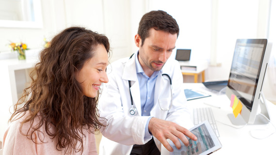 Ein Arzt erläutert einer Patientin die Diagnose an einem Tablet.