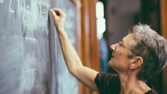 Mathematik-Lehrerin schreibt Formeln mit Kreide an die Tafel